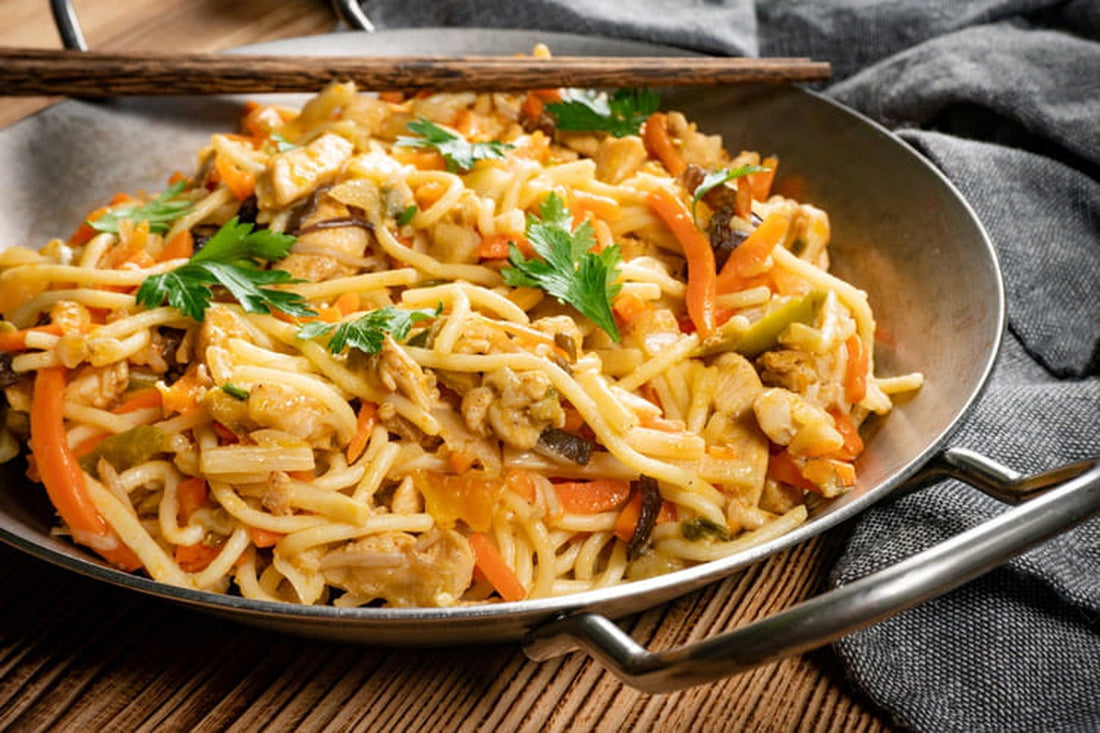 Chow mein met kip, paksoi en noedels in een wok