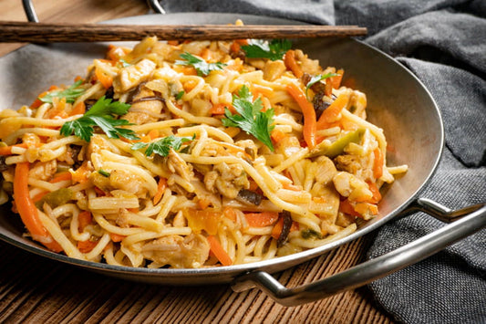 Chow mein met kip, paksoi en noedels in een wok