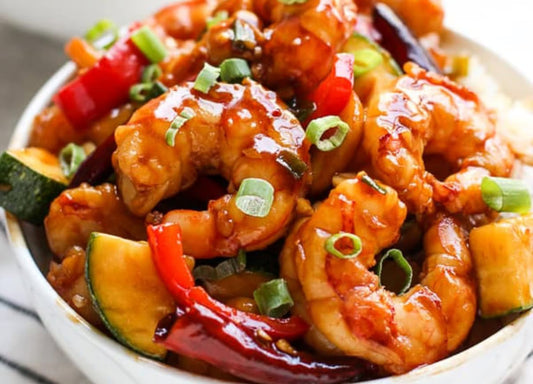 Garnalen in ketchupsaus geroerbakt in een wok, geserveerd met witte rijst