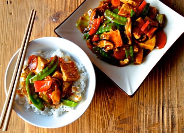 Gesmoorde tofu met suikererwten, wortel en paprika in een wok met glanzende saus