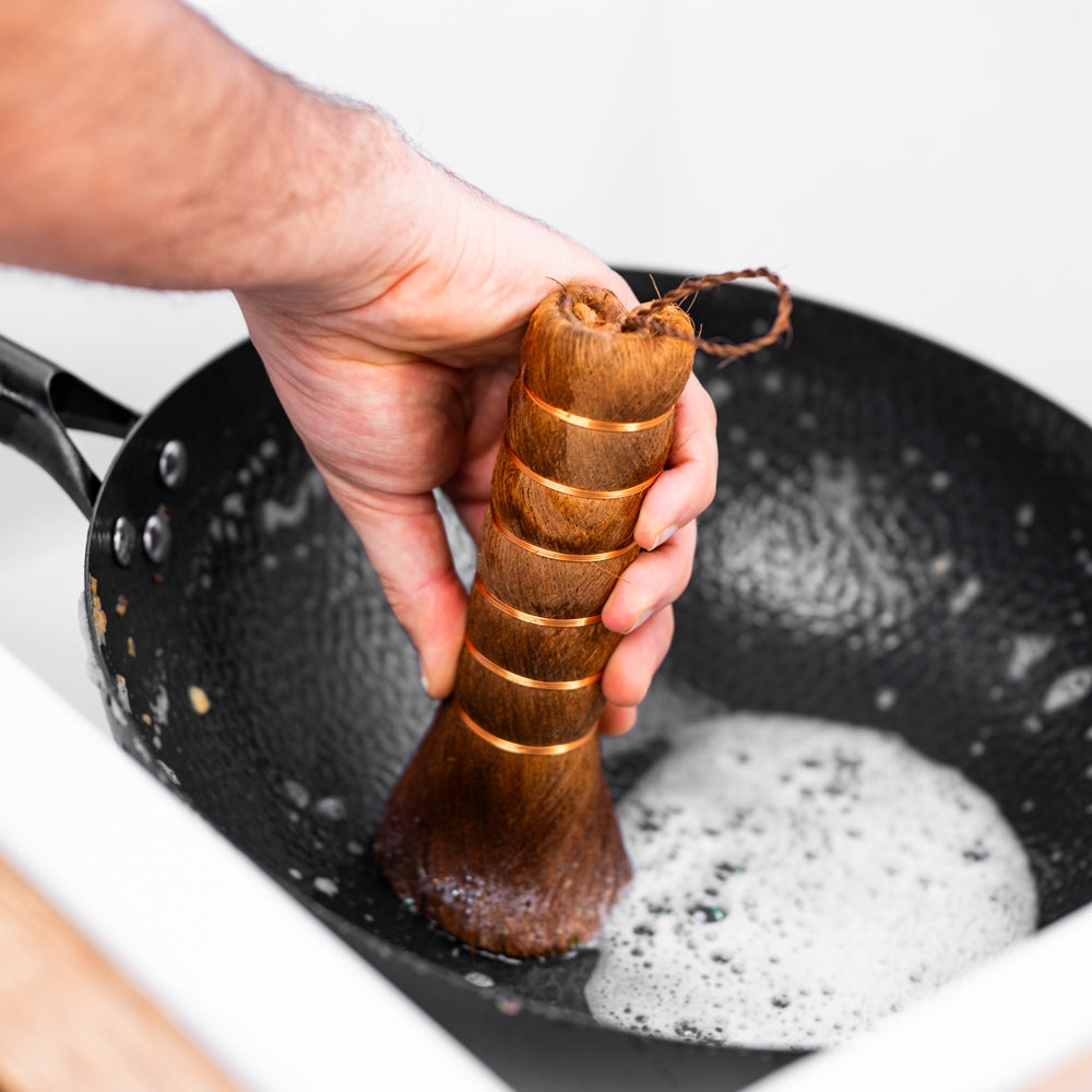 Le Pakia palm wok schoonmaakborstel in gebruik bij het schrobben van wok
