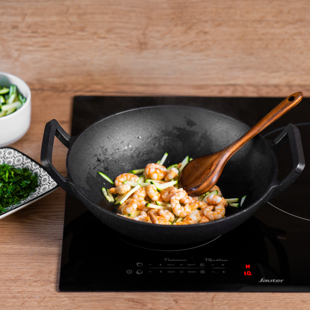 Le Tekari gietijzeren wok zonder steel verhit op de kookplaat