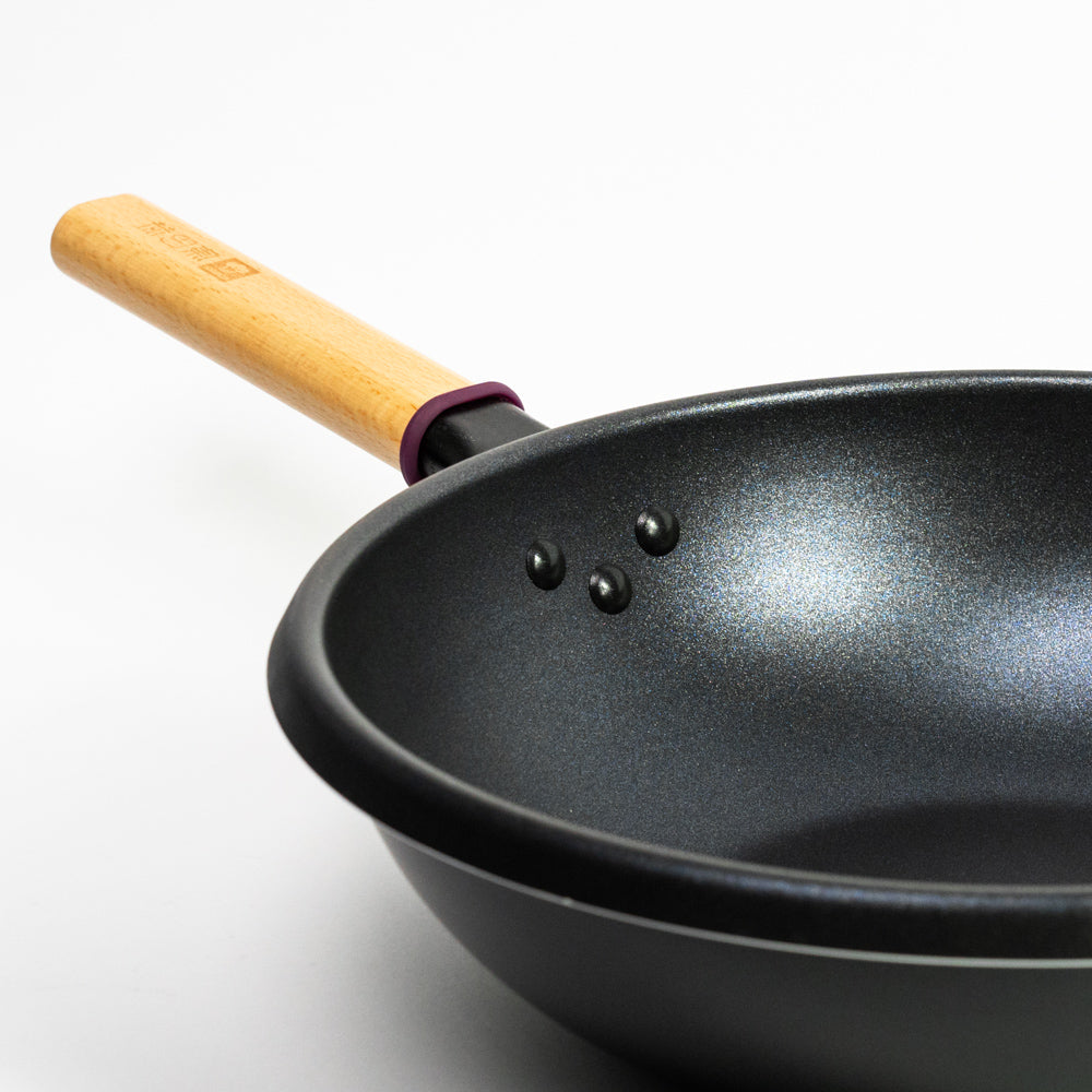 Le Amagi koolstofstaal wok met antikleeflaag – detail van het houten handvat