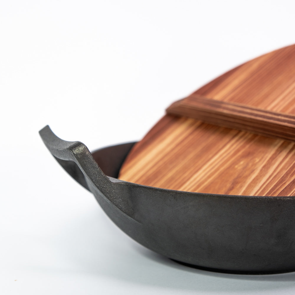 Le Tekari gietijzeren wok zonder steel in de hand gehouden