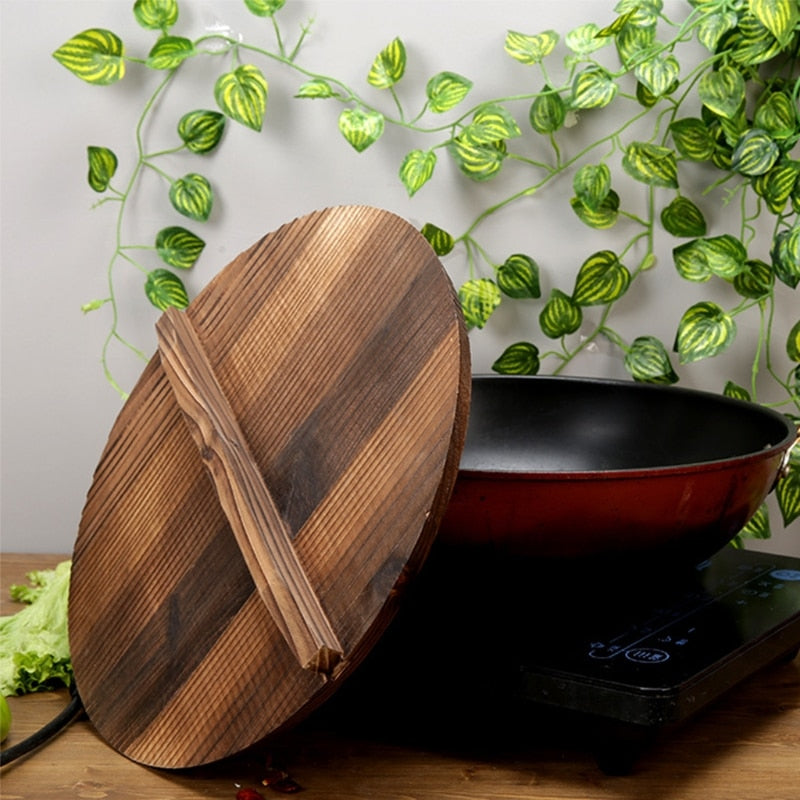 Le Ginsa houten deksel voor wok liggend op gloeiende wok tijdens het koken