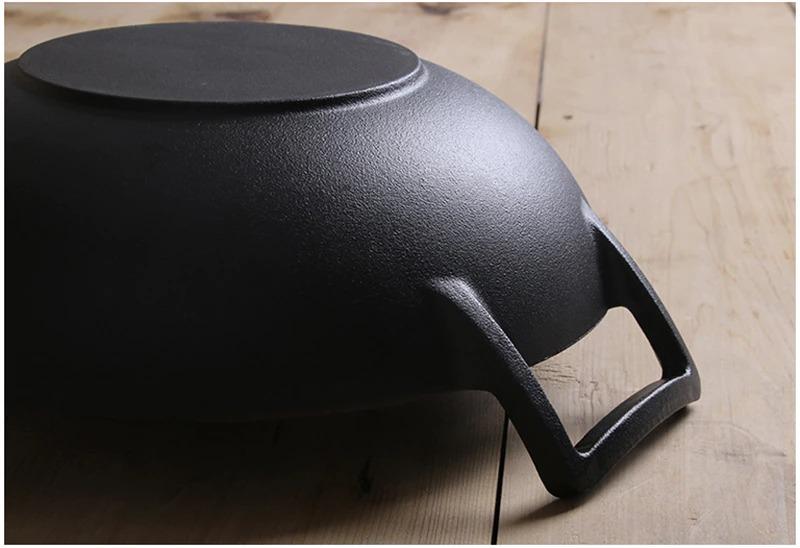 Le Fulan gietijzeren wok met twee oren in gebruik met houten spatel